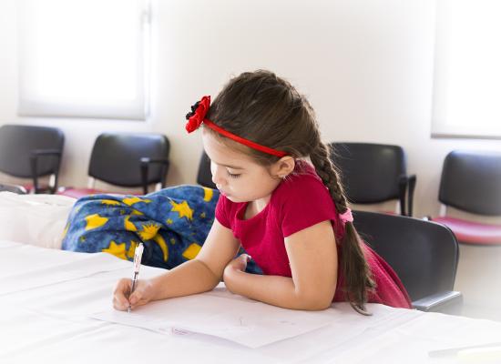 young girl sitting at desk and writing on paper