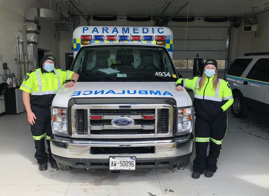 Two paramedics standing beside an ambulance